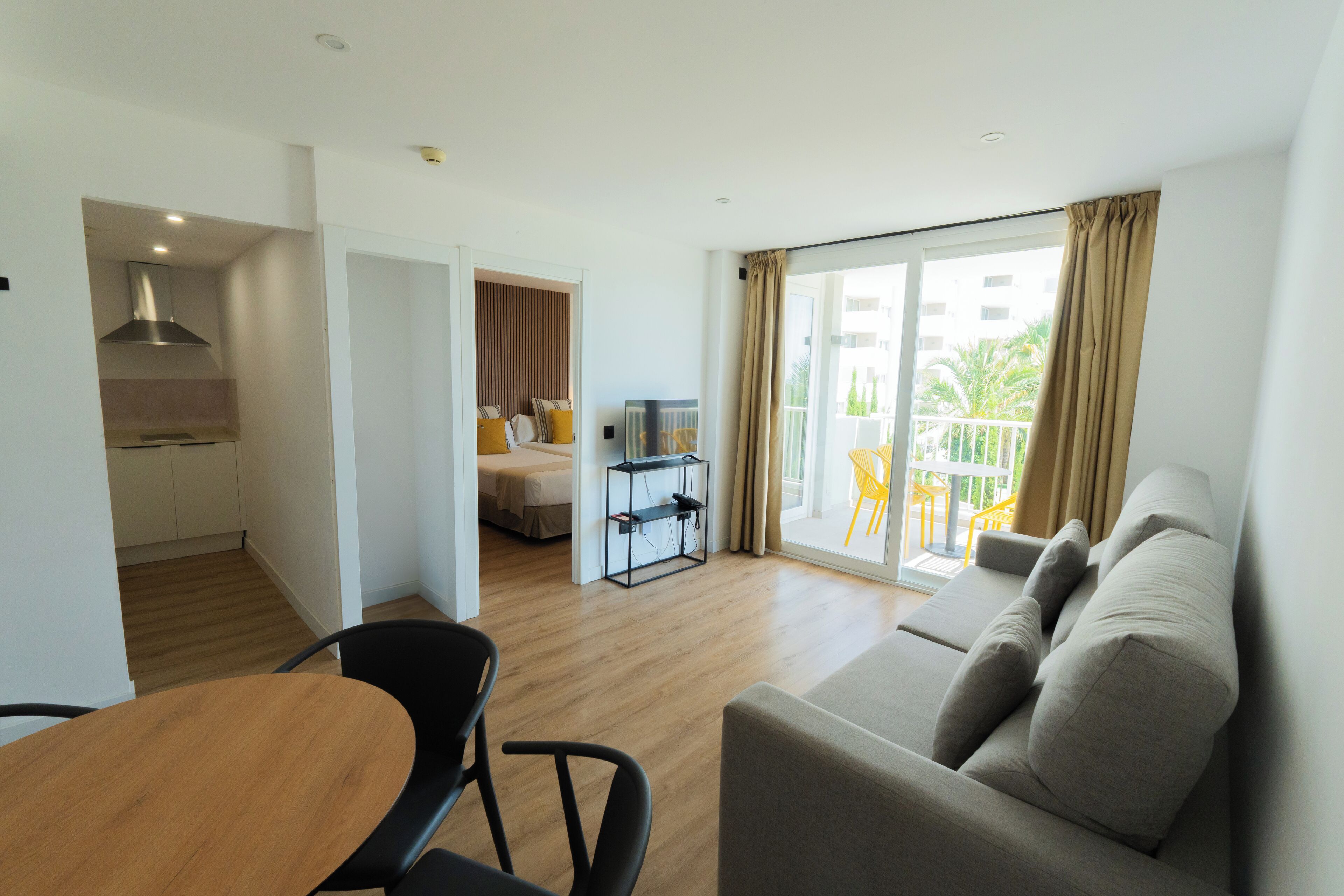 A modern living room with a sofa, a dining table, and a kitchen area.