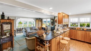 A spacious kitchen with wooden cabinets, a central island with stools, and a dining area with a sofa and chairs.