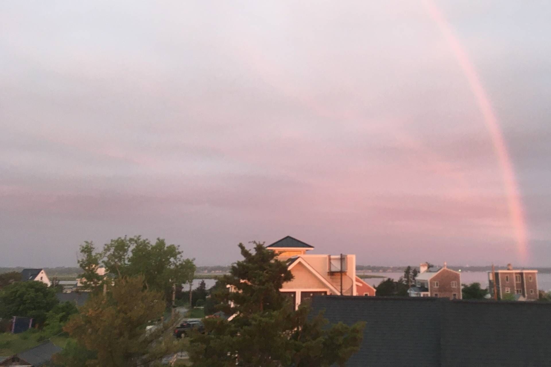 Un quartier résidentiel avec des maisons et un arc-en-ciel dans le ciel.