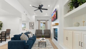 A modern living room with a blue sofa, two armchairs, a coffee table, and a fireplace.