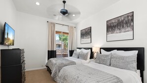 A bedroom with two beds, a dresser, and a television.