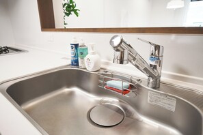 Ein Spülbecken aus Edelstahl mit modernem Wasserhahn, Seifenspendern und einer Seifenschale.
