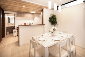 Eine moderne Küche mit Holzschränken, einer weißen Arbeitsplatte und einem Essbereich mit einem für sechs Personen gedeckten Tisch.