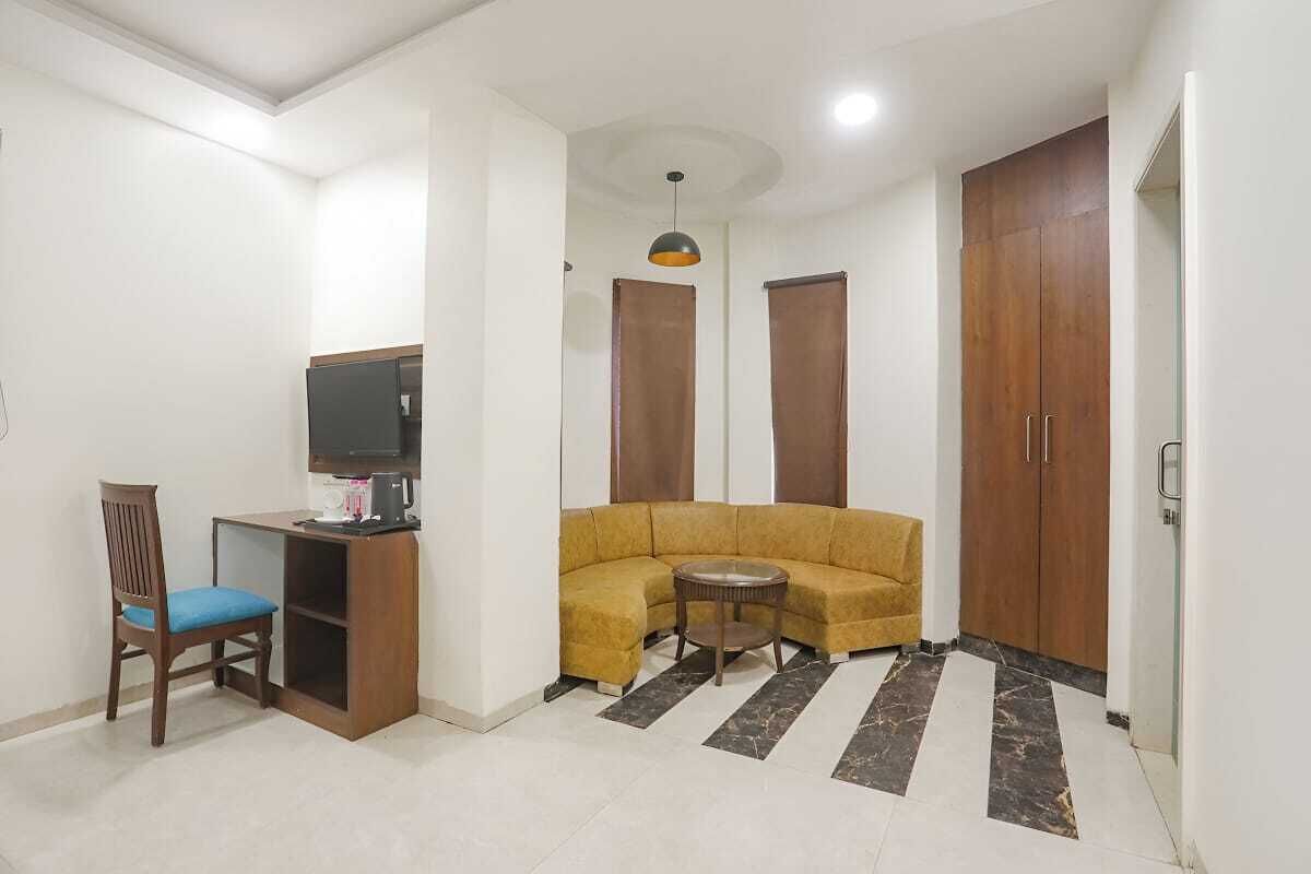 A living room with a sofa, a chair, a small table, a television, and a wardrobe.
