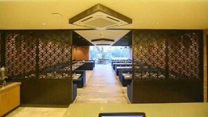 Een hotel lobby met een middellange gang die leidt naar een zithoek, decoratieve wandpanelen en een receptiebalie.