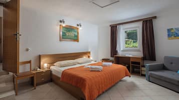 A bedroom with a bed, bedside tables, a desk, a chair, a window with curtains, and a painting on the wall.