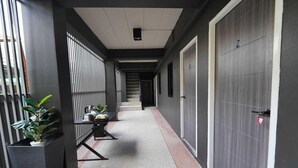 A corridor with a staircase, a door with a lock, and potted plants.