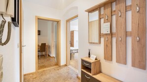 A hallway with wooden flooring, a desk with chairs, and a wooden cabinet with drawers. - Apartment 'Weida' with Wi-Fi (Riesa)