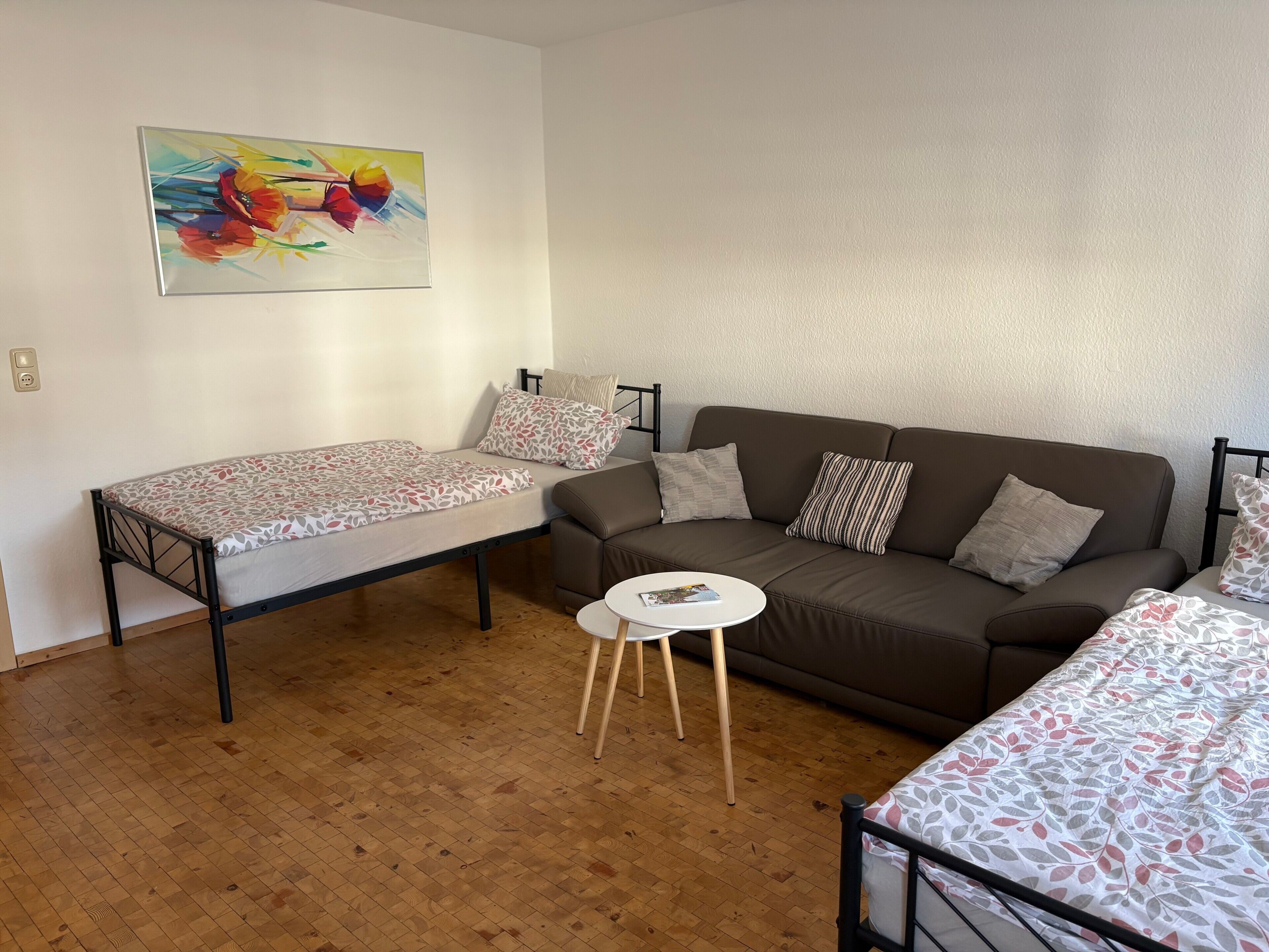 Une chambre meublée avec un lit, un canapé, une petite table et un tableau au mur.