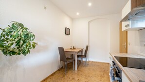 A compact kitchen with a dining table, chairs, a stove, and a potted plant. - Apartment 'Weida' with Wi-Fi (Riesa)