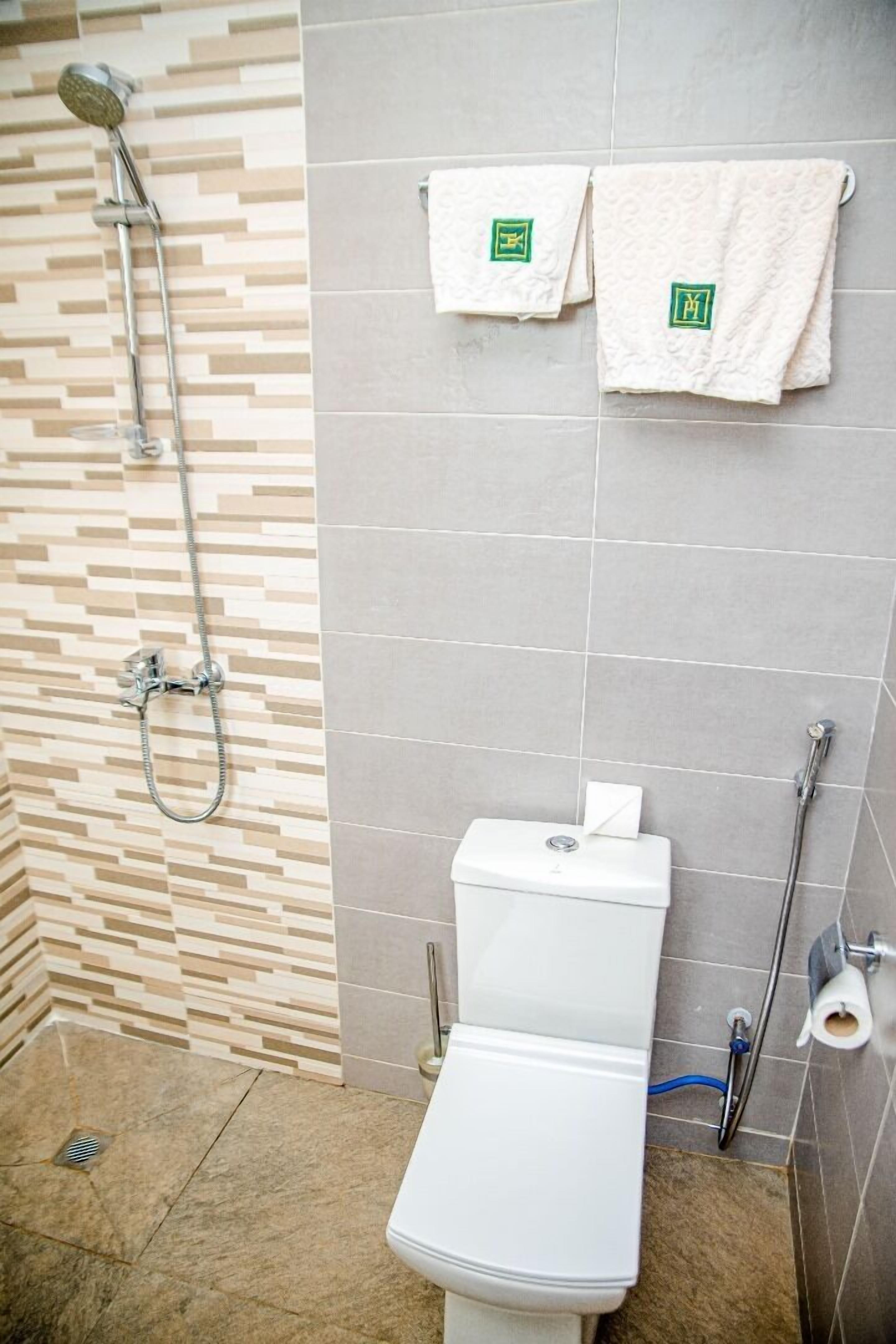 A bathroom with a shower, toilet, and towel rack.