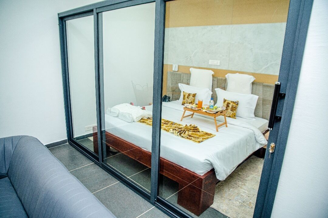 Quarto de hotel moderno com uma cama, um sofá e um painel de vidro.