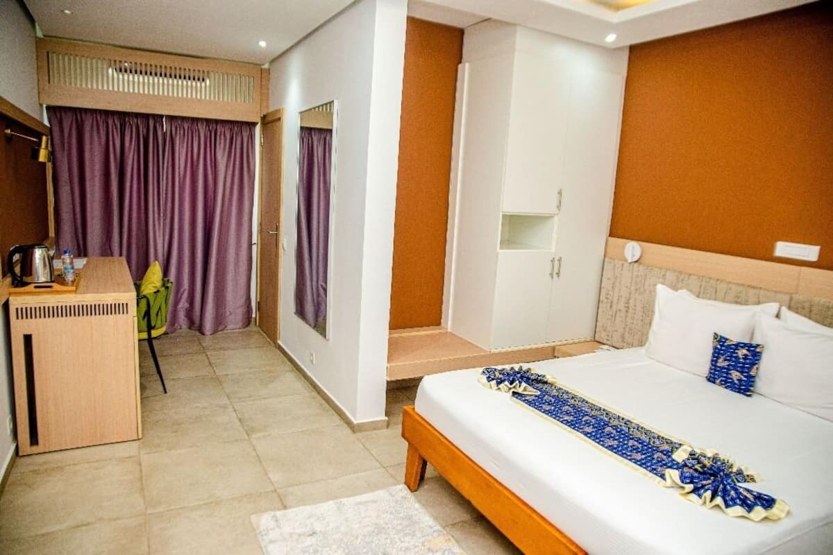 A hotel room with a bed, a desk, a chair, and a wardrobe.