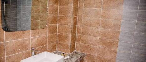 Une salle de bain avec un lavabo blanc, un miroir et des murs recouverts de carreaux bruns.