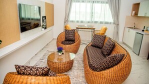 A modern living room with wicker furniture, a flat-screen TV, and a dining area. - HOTEL YATCHENIN YAMOUSSOKRO (Yamoussoukro)
