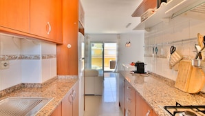 A kitchen with granite countertops, wooden cabinets, a built-in oven, and a dining area with a table and chairs. - All-inclusive penthouse with views in Denia (Denia)