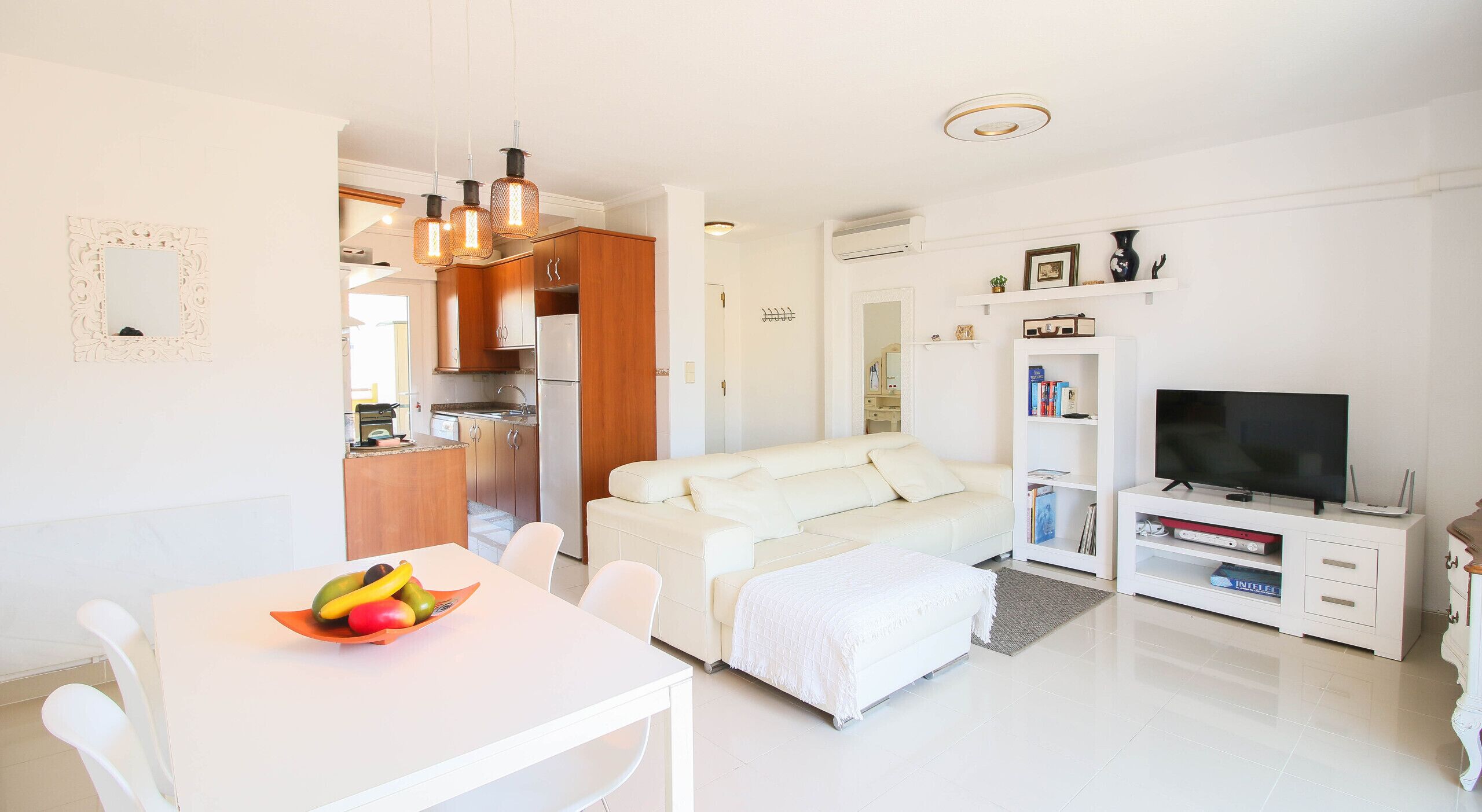 Un apartamento moderno con cocina, comedor, sala de estar y mueble para televisión.