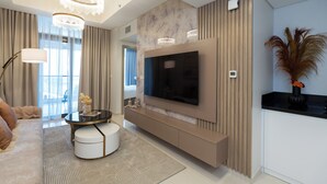 A modern living room with a large flat-screen TV, a round coffee table, and a sofa. - Keyrock Living - Luxury at Aykon Tower (Dubai)