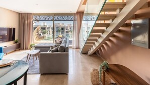 A modern living room with a sofa, a TV, and a staircase.