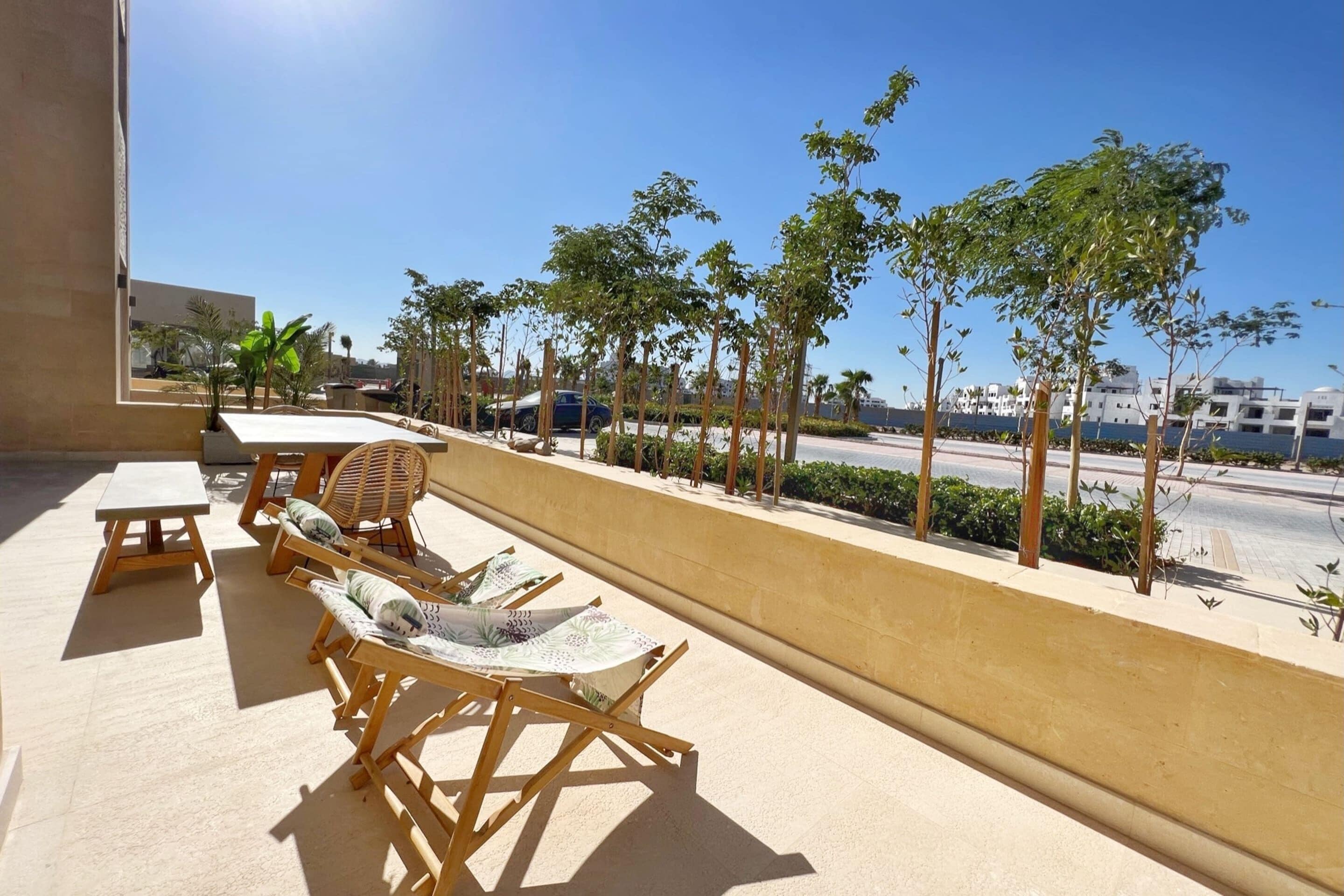 A terrace with wooden furniture and a view of a street and buildings.
