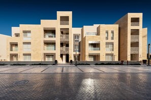 Un bâtiment moderne doté de nombreux balcons et d’un espace d’entrée pavé.