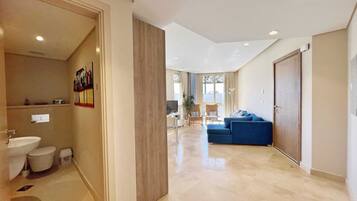A modern interior with a bathroom, a living area with a blue sofa, and a dining area with a table and chairs.
