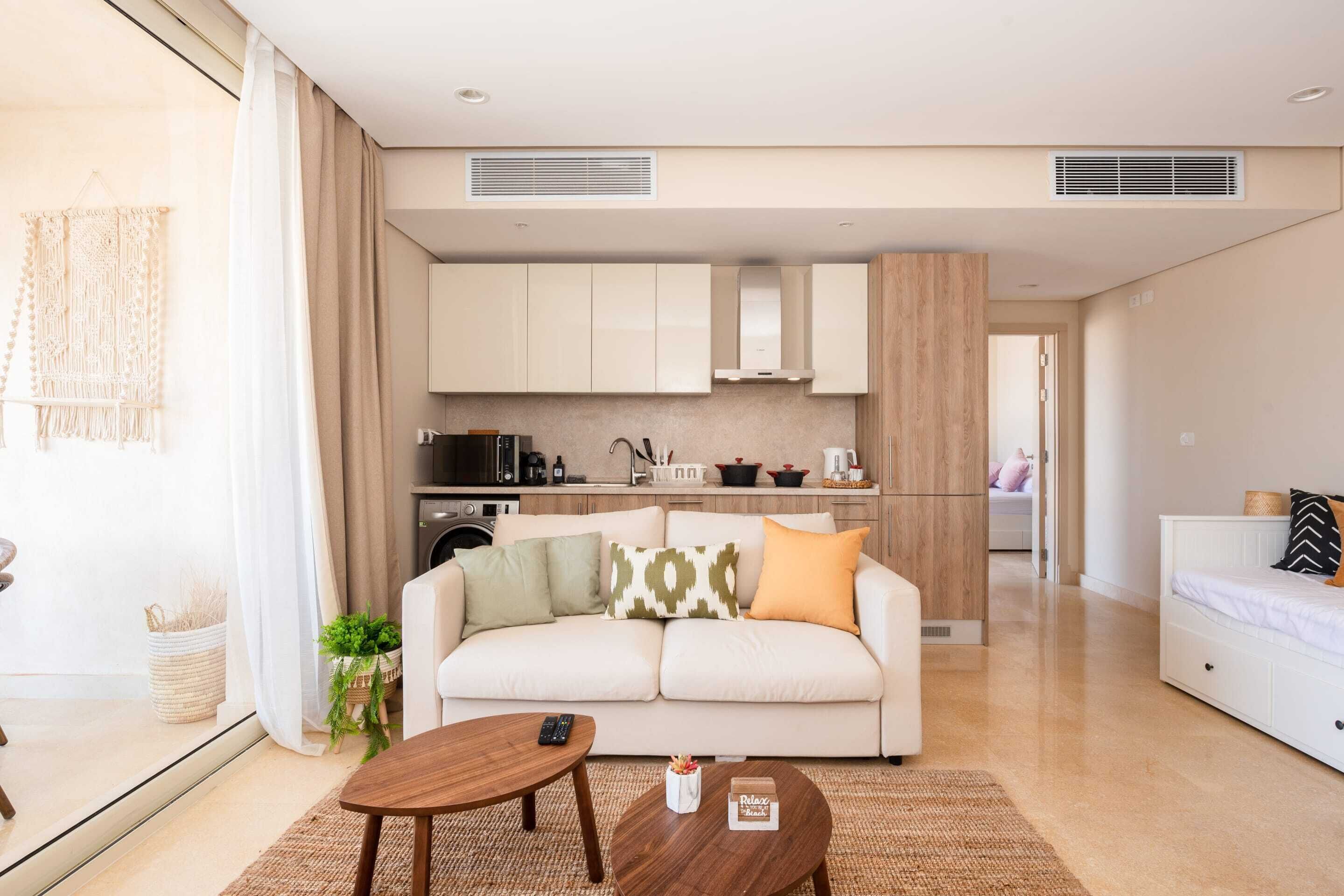 Ein modernes Wohnzimmer mit Sofa, Couchtisch und einer Küche im Hintergrund.