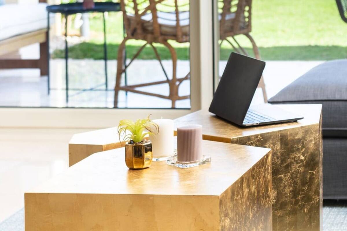 Un comptoir d’accueil avec un ordinateur portable, une plante en pot et une bougie.