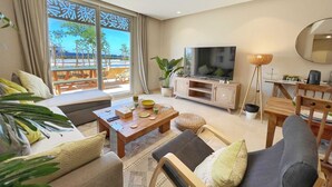 A modern living room with a sofa, coffee table, TV, and a view of the outdoors.
