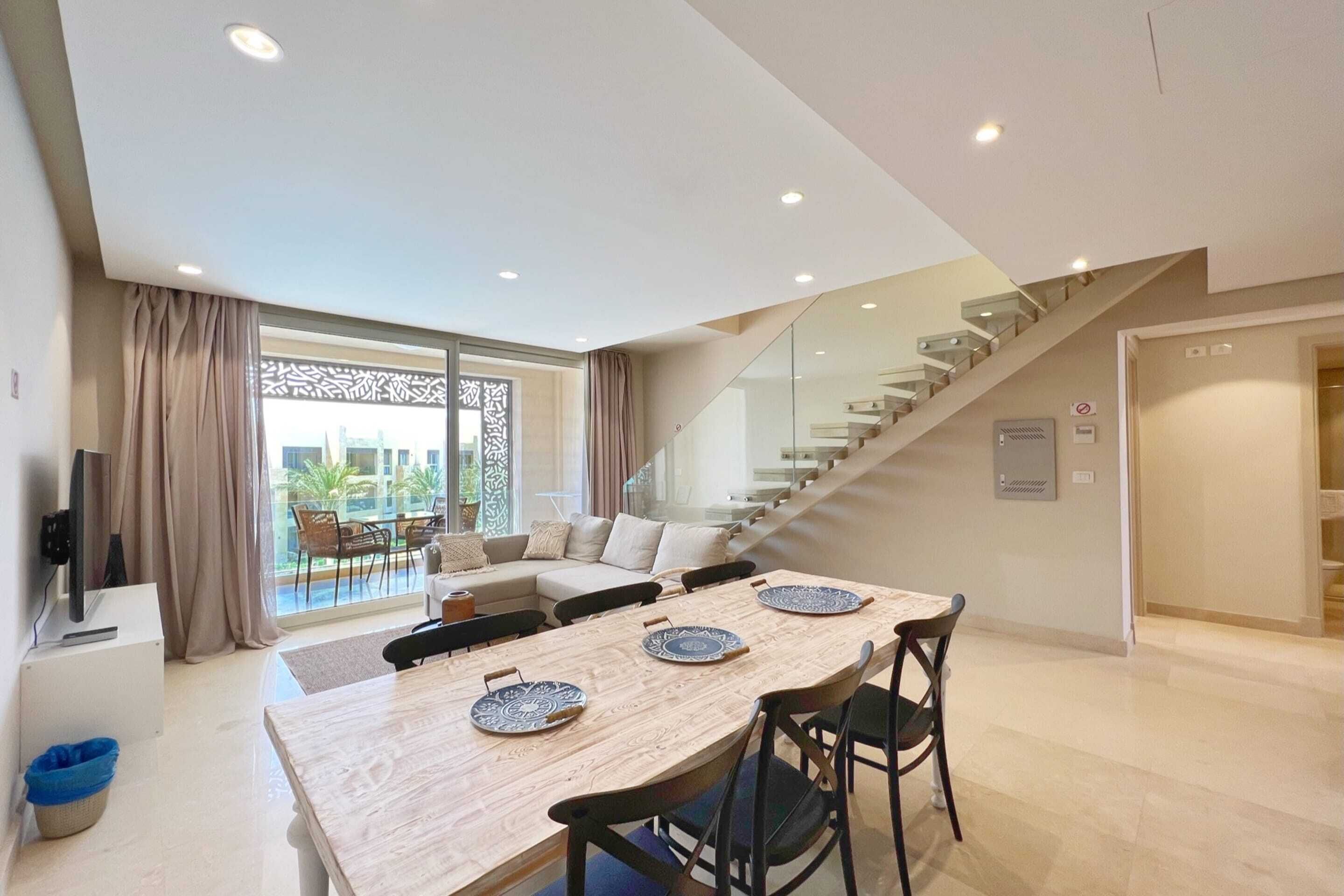 Un salon moderne avec une table à manger, un canapé et un escalier.