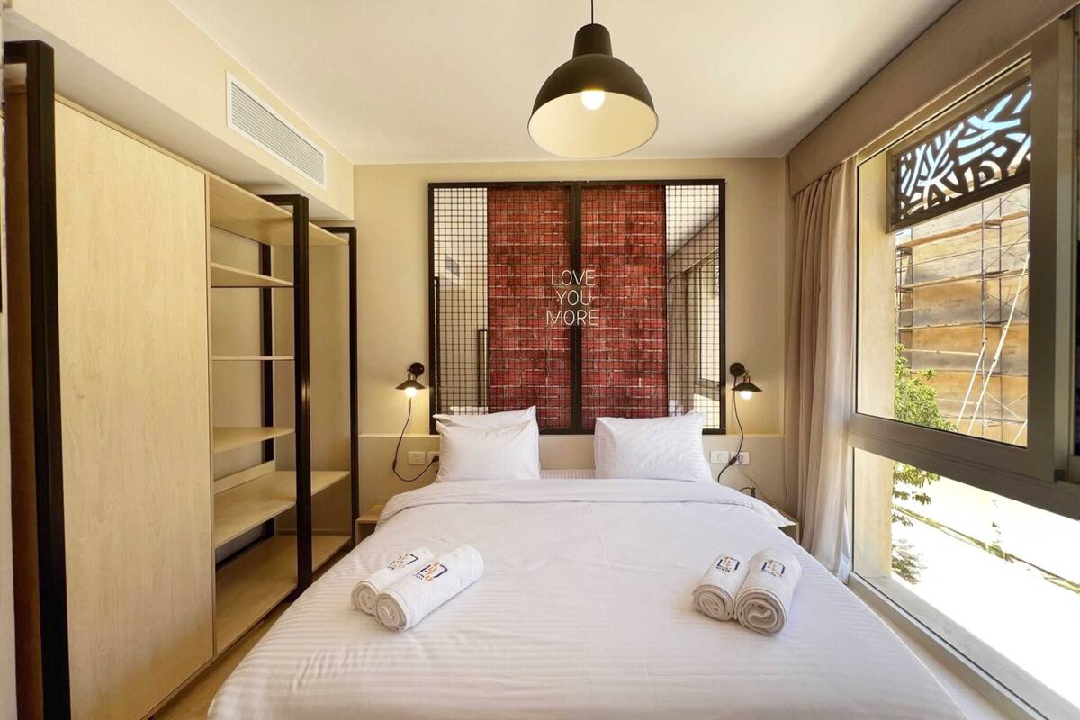 Une chambre d’hôtel comprenant un lit, deux lampes de chevet, une fenêtre avec vue, une armoire et un élément décoratif mural.