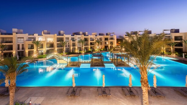A large swimming pool with multiple lanes, surrounded by palm trees and lounge chairs.