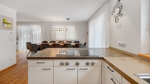 Een moderne keuken met een centraal kookeiland, witte kastjes en een eethoek met een tafel en stoelen.