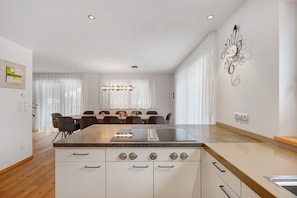 A modern kitchen with a central island, white cabinetry, and a dining area with a table and chairs.