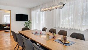 Een moderne eethoek met een houten tafel, stoelen en een hanglamp.