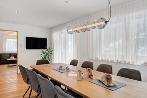 A modern dining area with a wooden table, chairs, and a hanging light fixture.
