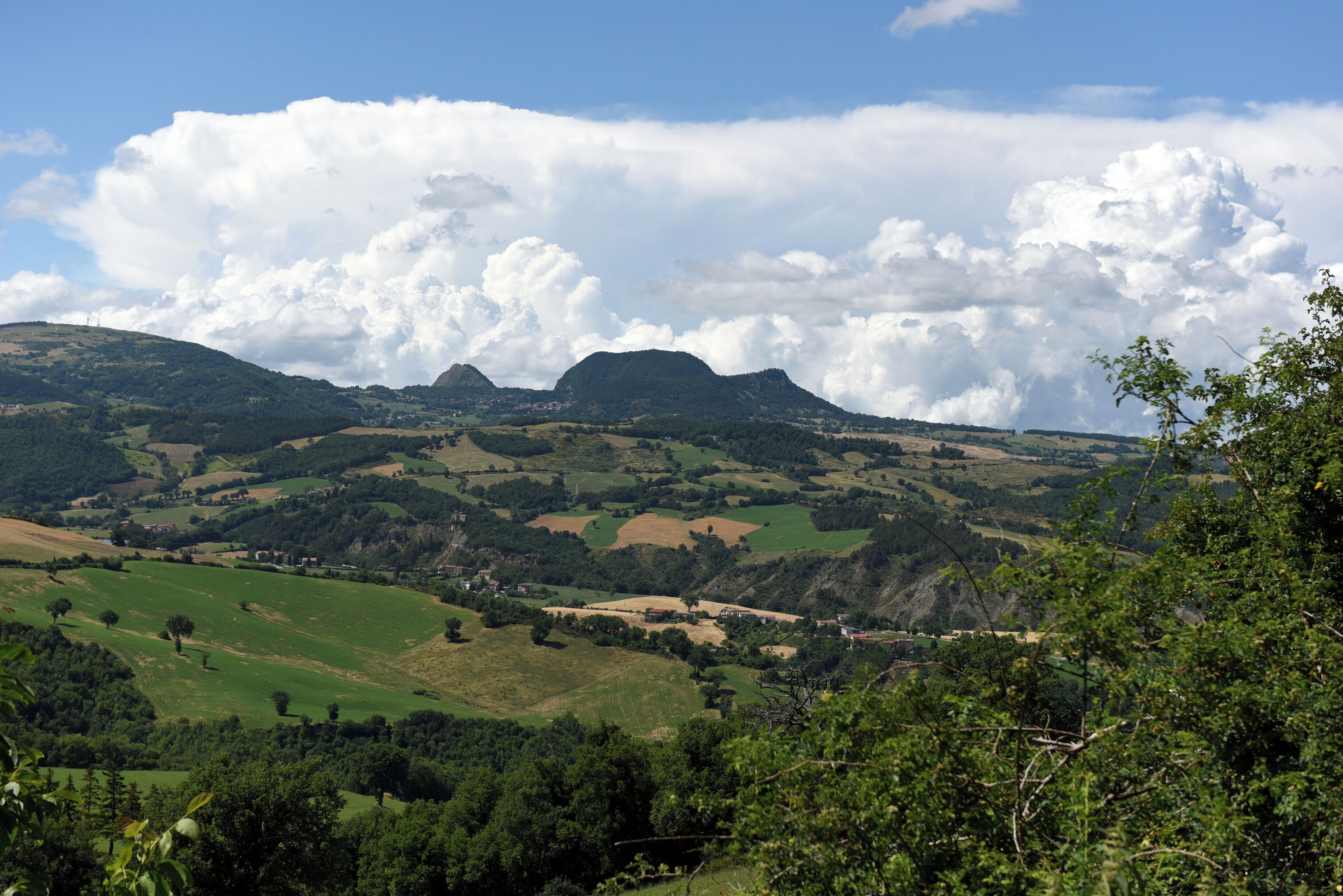 Een panoramisch uitzicht op een heuvellandschap, met een opvallende berg op de achtergrond en een heldere lucht.