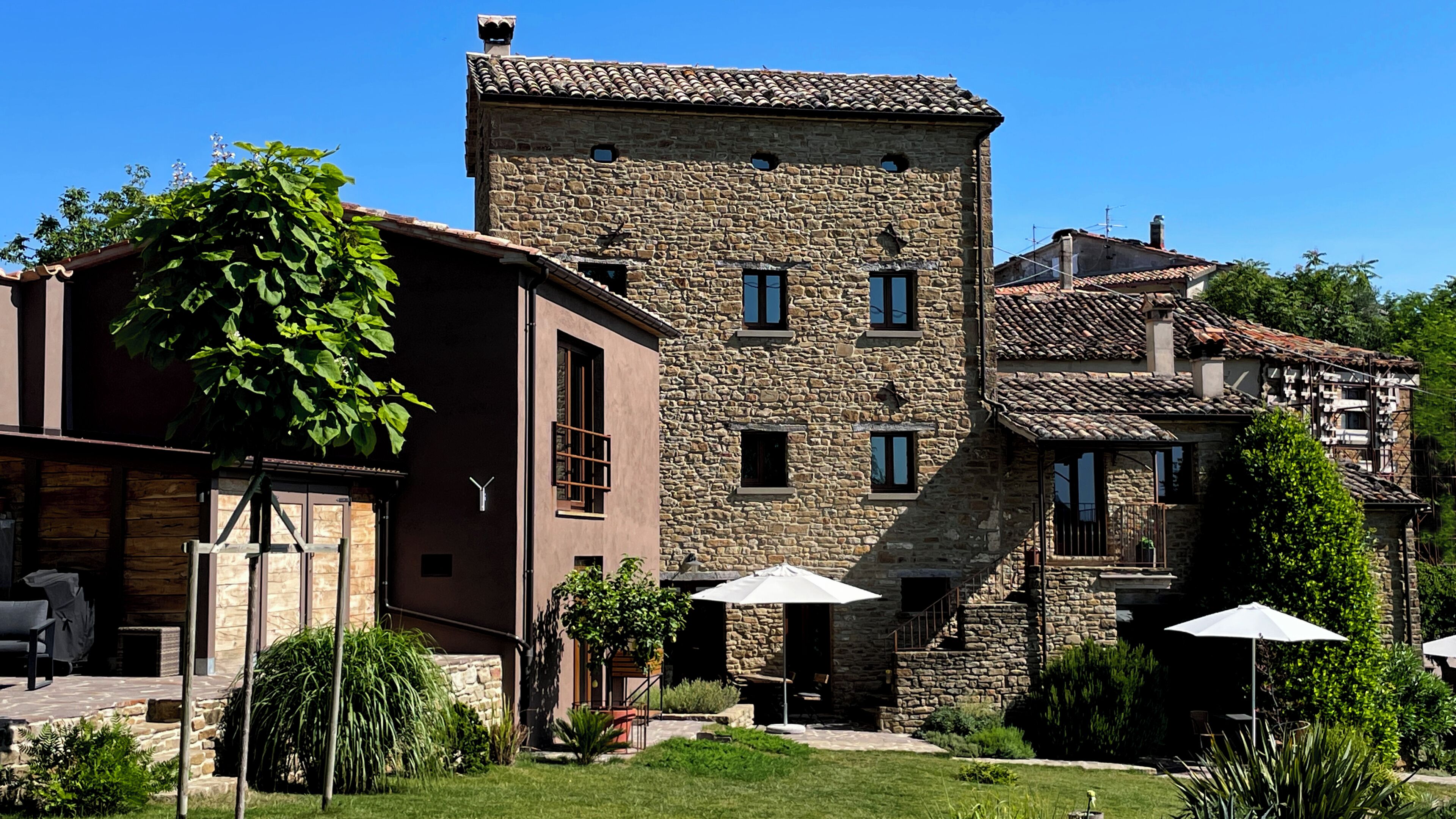 A stone building with a courtyard, outdoor seating, and a staircase leading to an upper level.