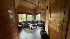 A wooden cabin interior with a sofa, coffee table, and a door. - Villa Slalom 2, Himos Länsihuippu (Keski-Suomi)