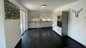 A modern kitchen with white cabinets, a built-in microwave, and a large refrigerator. - Holiday Home 'Ferienhaus Rechlin' with Private Terrace, Private Garden and Wi-Fi (Rechlin)