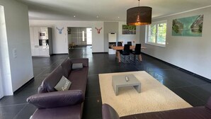 A modern living space with a sofa, coffee table, dining area, and kitchen. - Holiday Home 'Ferienhaus Rechlin' with Private Terrace, Private Garden and Wi-Fi (Rechlin)