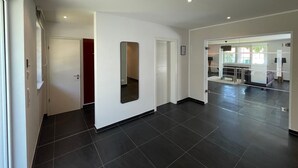 A modern interior with a hallway leading to a living area, featuring a glass partition, recessed ceiling lights, and a tiled floor. - Holiday Home 'Ferienhaus Rechlin' with Private Terrace, Private Garden and Wi-Fi (Rechlin)