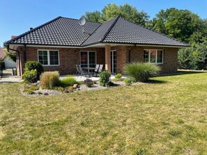 A two-story house with a brick exterior, a dark tiled roof, and a covered patio area with outdoor furniture. - Holiday Home 'Ferienhaus Rechlin' with Private Terrace, Private Garden and Wi-Fi (Rechlin)
