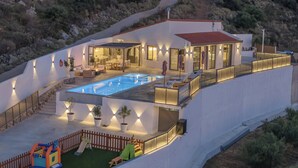 Une villa moderne dotée d’une piscine, d’un espace salon extérieur et offrant une vue panoramique sur les collines environnantes.
