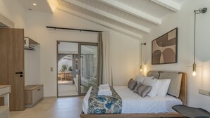 Une chambre moderne avec un grand lit, une table de chevet en bois, un bureau et une porte-fenêtre coulissante donnant sur un espace extérieur.