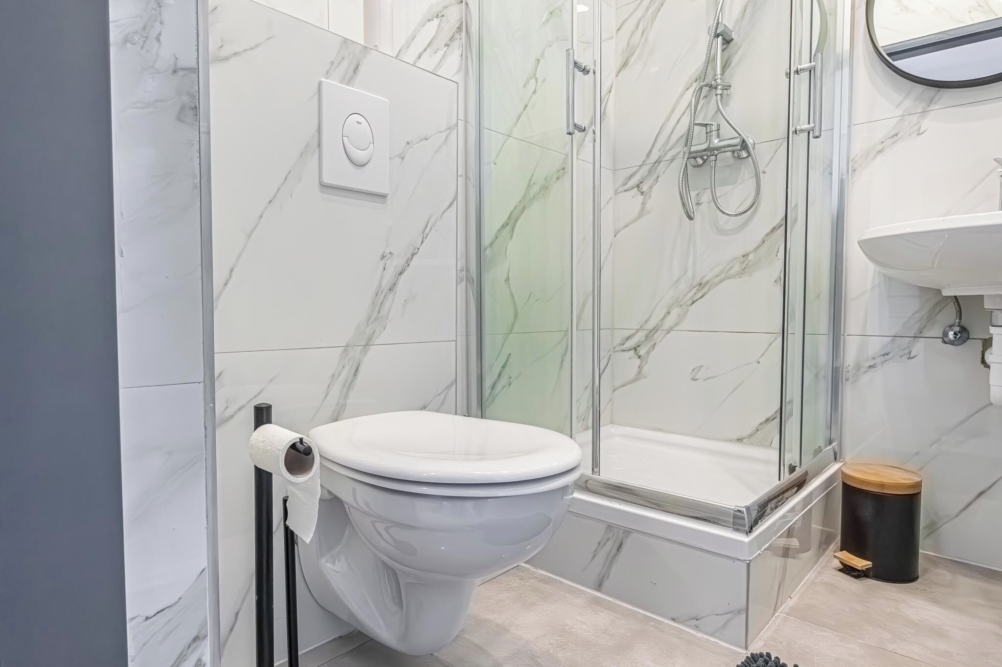 Une salle de bain moderne équipée de toilettes, d’une douche à parois de verre et d’un lavabo.