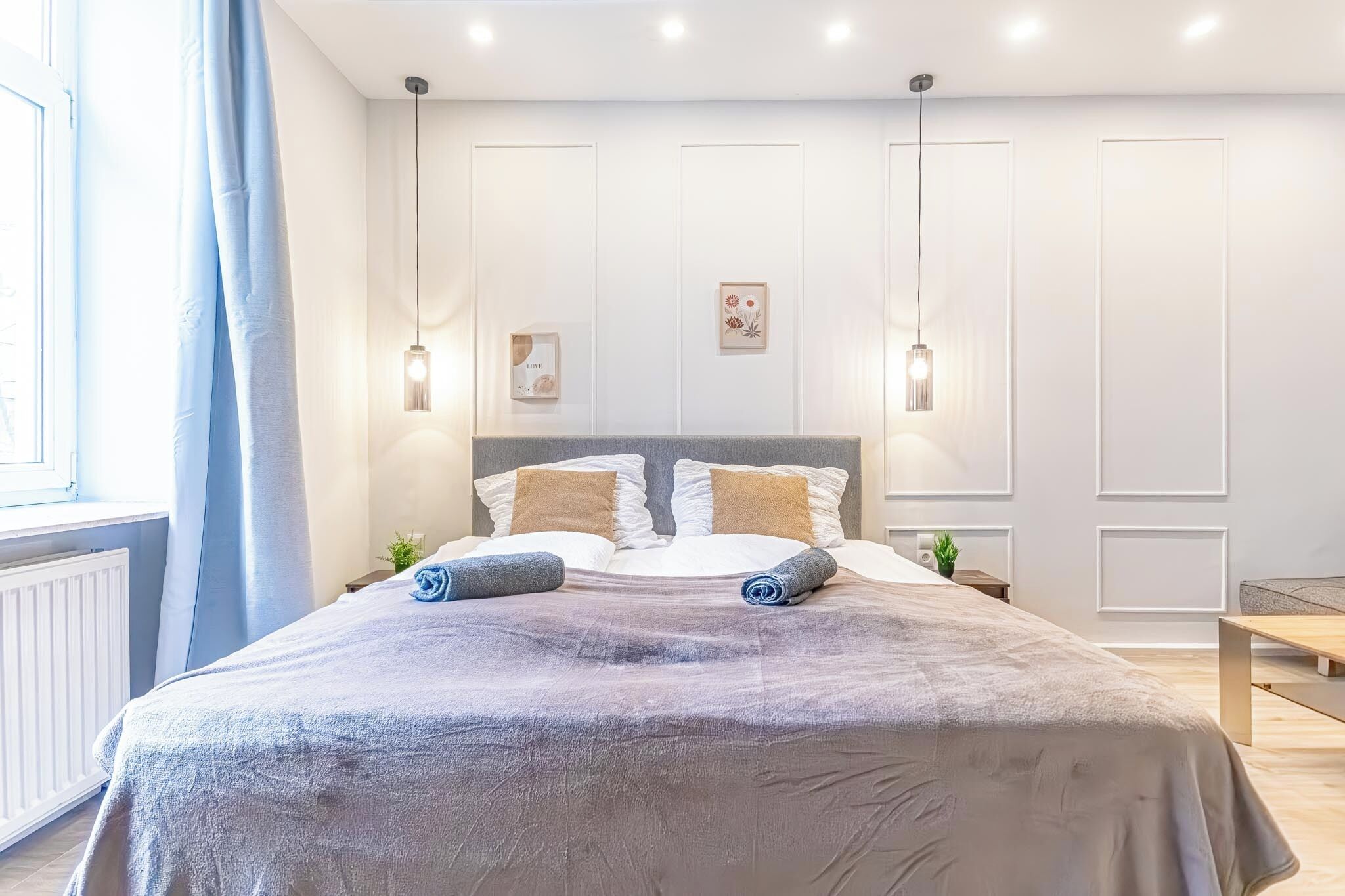 Quarto moderno com uma cama grande, duas mesas de cabeceira e uma janela com cortinas.