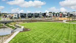 A modern residential area with contemporary houses, a central green space, and a small water feature.
