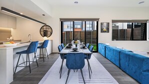 A modern kitchen with a dining area, a sofa, and a view of the city.