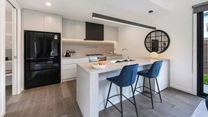 A modern kitchen with a central island, black refrigerator, and a round mirror on the wall.